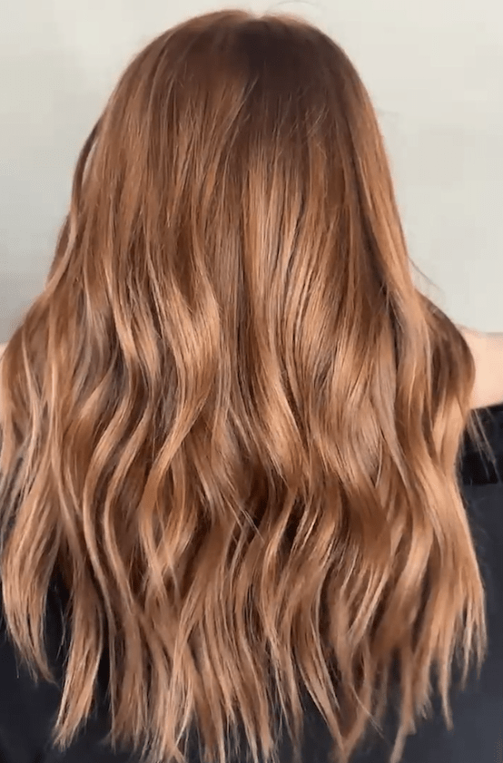 A woman's back view with long, wavy hair cascading down her shoulders.
