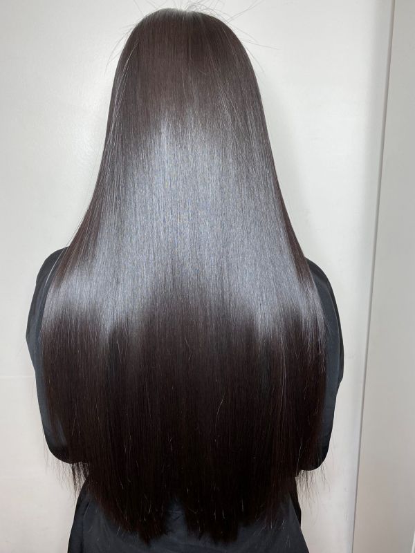 A woman's back of the head with long, straight hair cascading down her shoulders.
