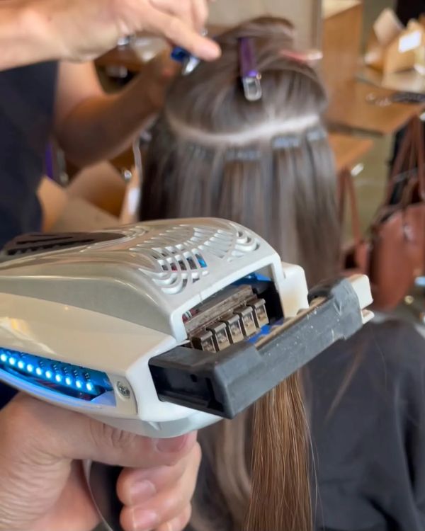 A person using a hair straightener to cut hair, demonstrating a unique hairstyling technique.