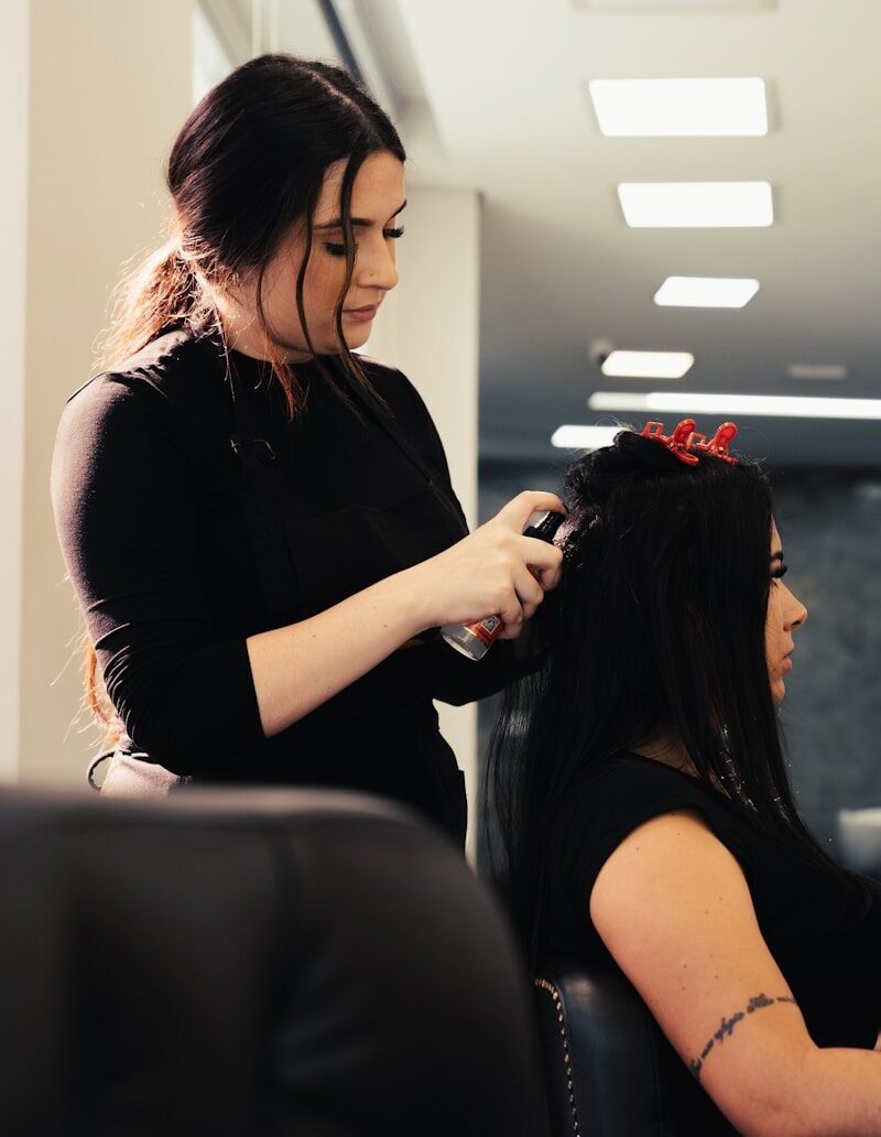 a woman cutting another woman's hair in a salon